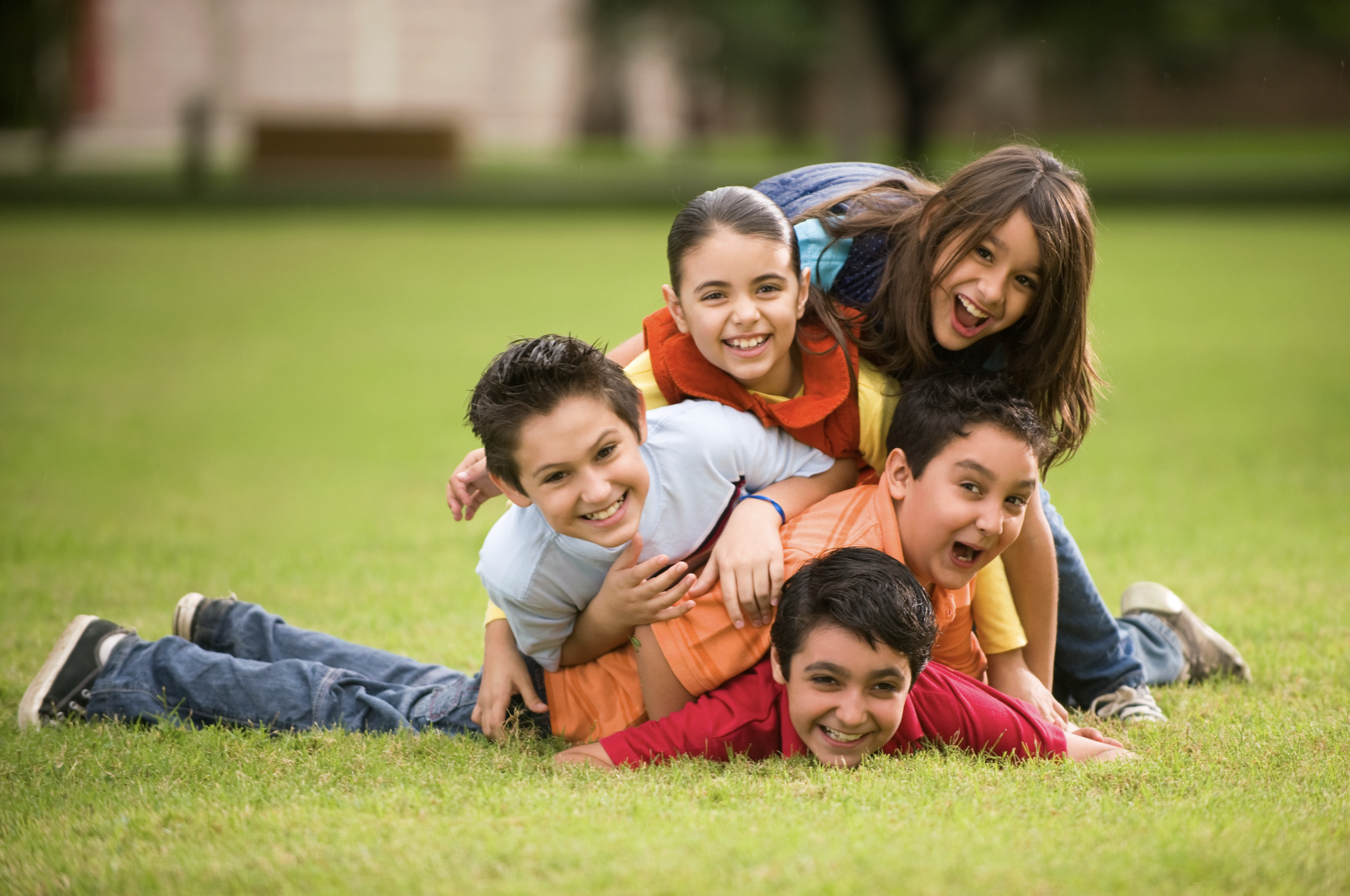 Cinco niños apilados y riendo sobre el césped
